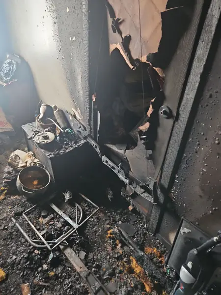 Fire-damaged room with charred debris and soot-covered walls