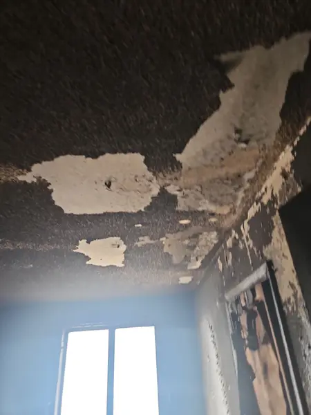 Smoke-blackened ceiling with peeling texture after a fire