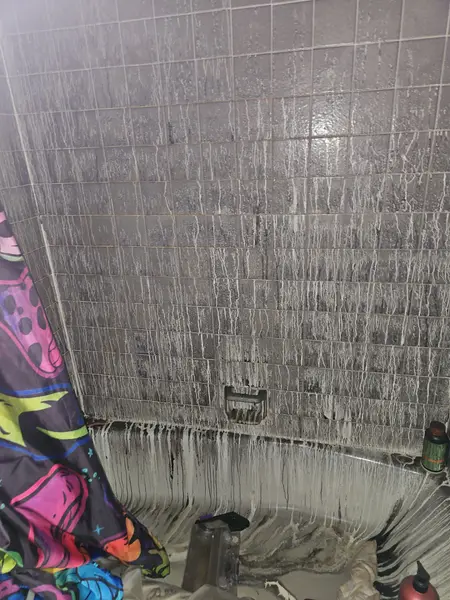 Soot-covered shower tile during fire cleanup